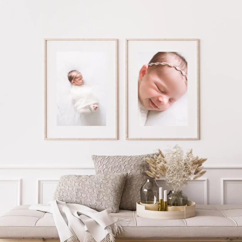 Two framed photos of a sleeping newborn baby hang on a white wall above a cushioned bench. The bench has patterned throw pillows and a decorative tray with dried flowers and candles. The scene is calm and cozy. Kristin Milito Photography - Newborn & Maternity Photographer - Chicago IL