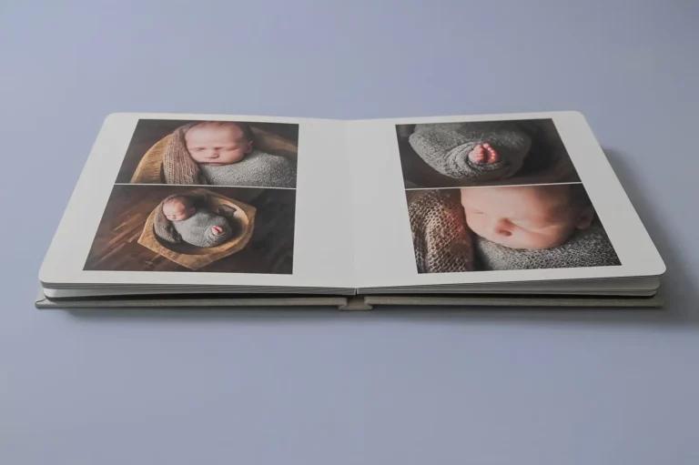 An open photo album on a light surface displays four photos by a Chicago Newborn Photographer, featuring a sleeping newborn wrapped in a gray blanket—close-ups of the baby’s face, feet, and a full-body shot in a basket. Kristin Milito Photography - Newborn & Maternity Photographer - Chicago IL