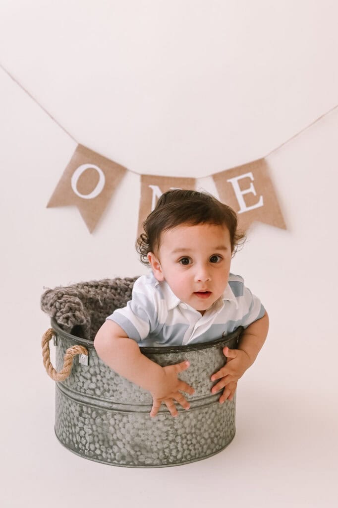Baby in bucket with 'one' banner decoration.
