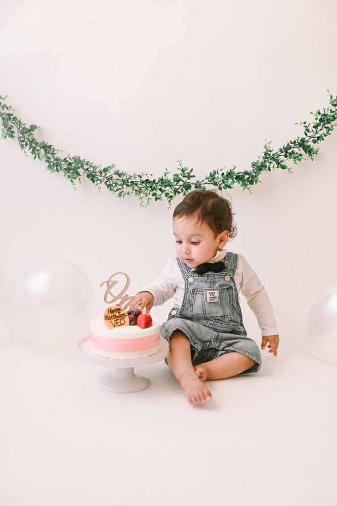 Toddler with birthday cake and decorations.