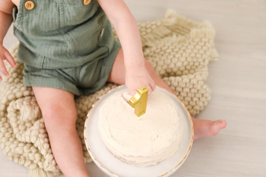 Baby celebrating first birthday with cake.